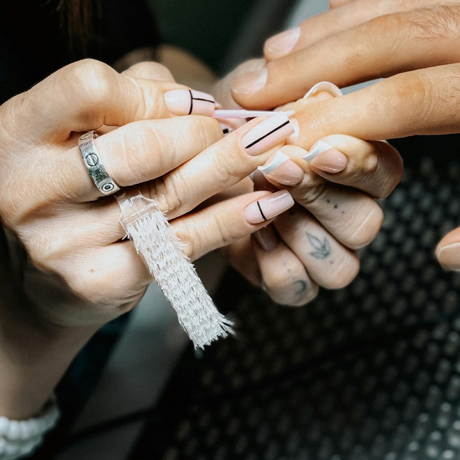 Manicurist filing a pale pink manicure during a salon service