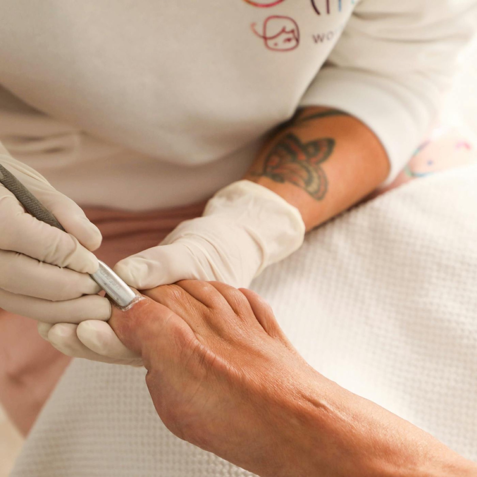 Manicurist using an electric file while shaping a client's nails