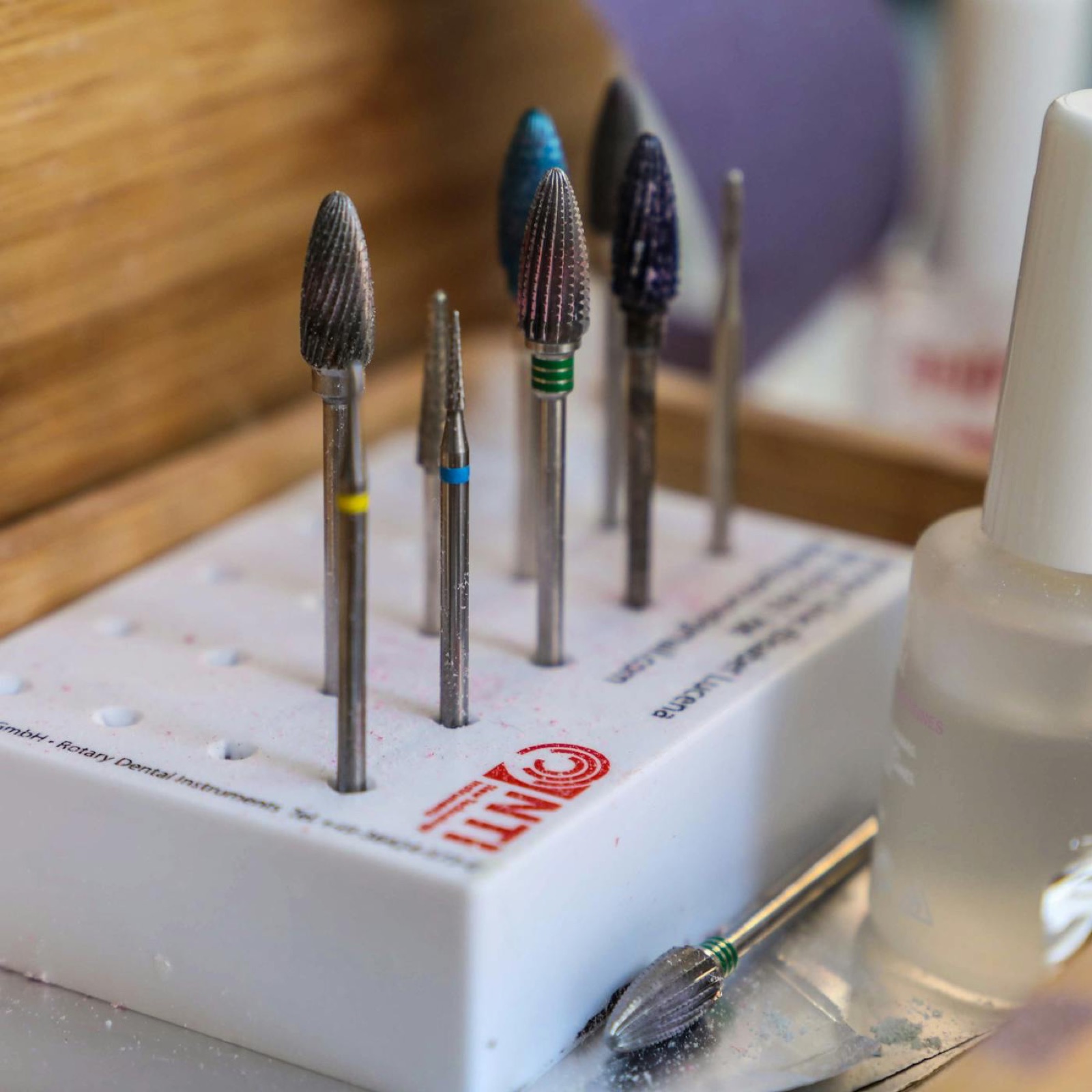 Nail drill bits and manicure tools arranged in a wooden tray