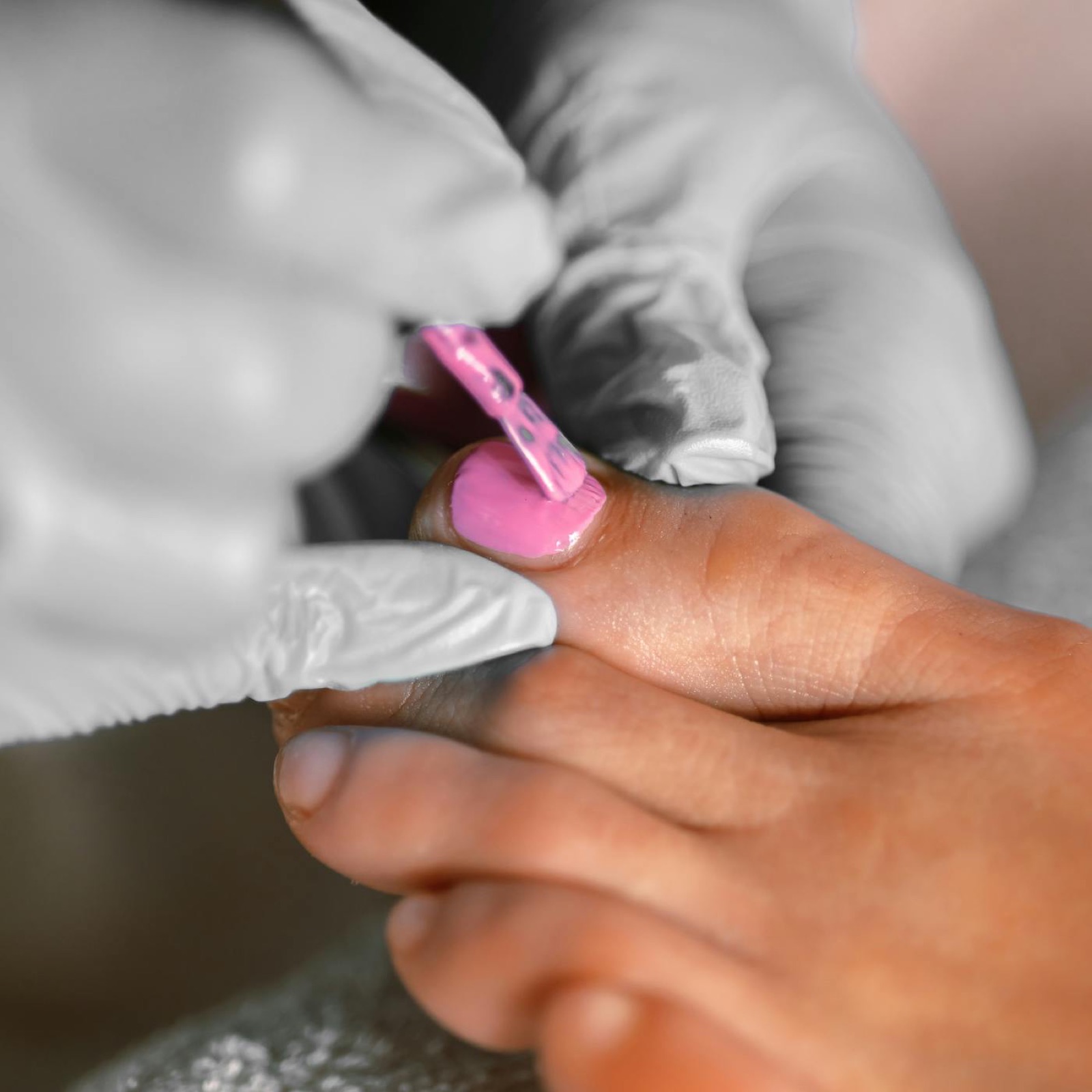 Close-up of a pedicure with bright pink polish being applied to a toenail